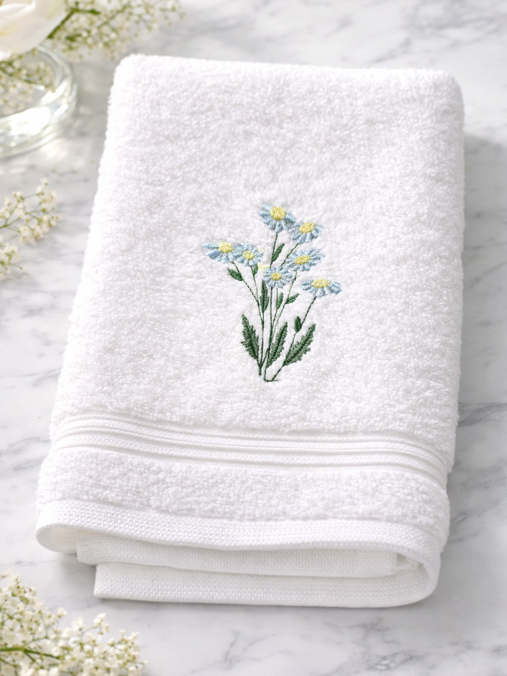 White towel with floral embroidery on a marble surface