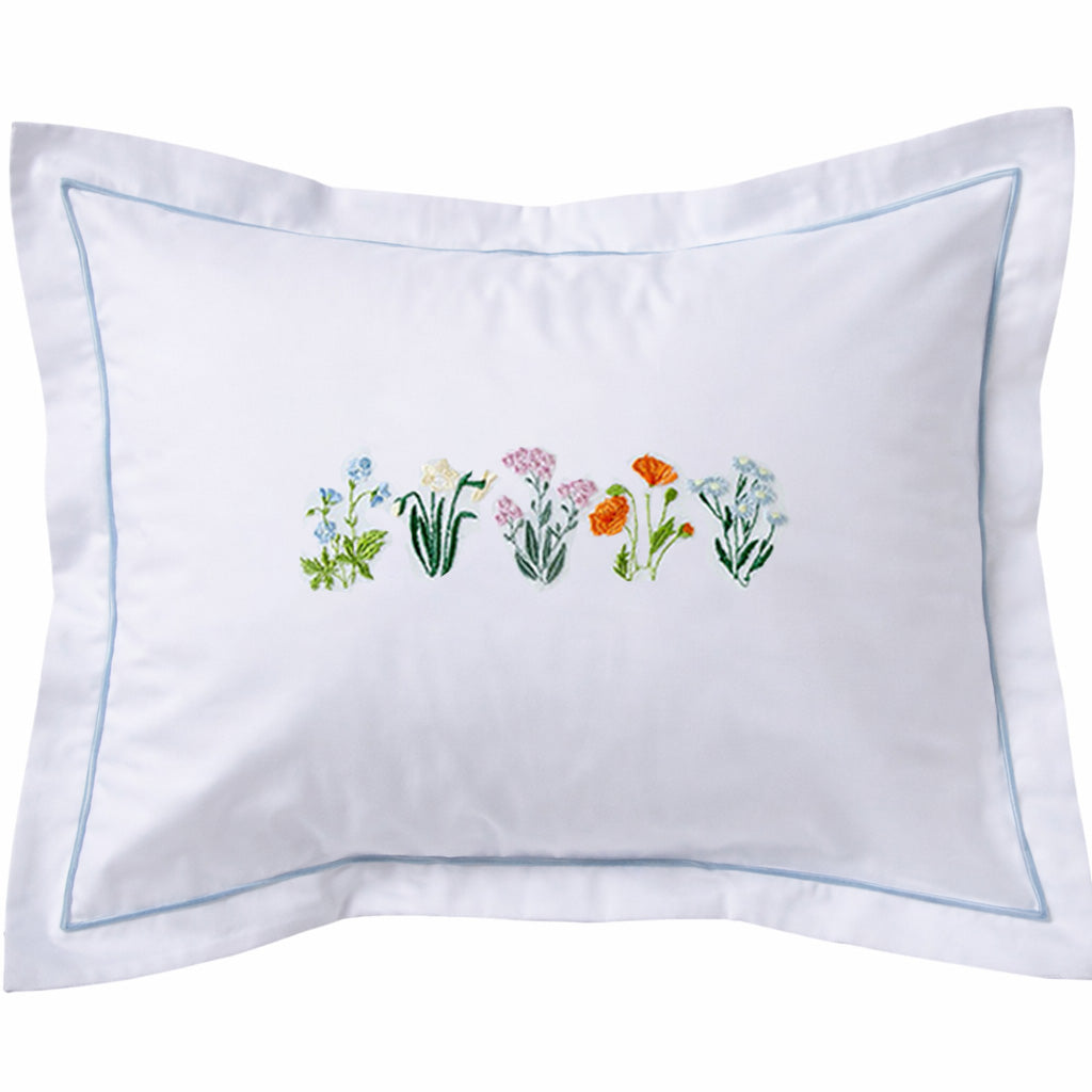 White pillow with embroidered floral design on a white background