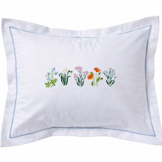 White pillow with embroidered floral design on a white background