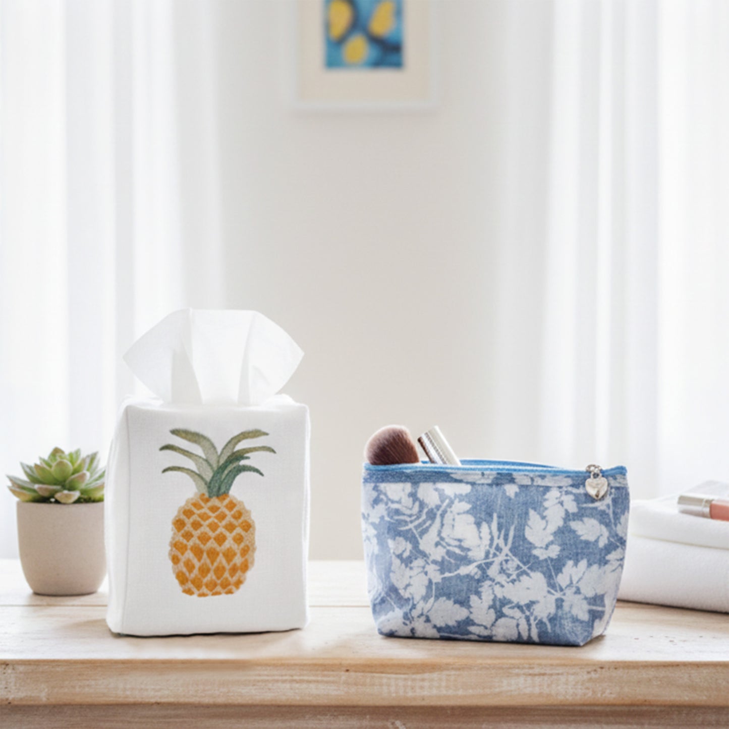 Tissue box with pineapple design and floral-patterned basket on a wooden surface.