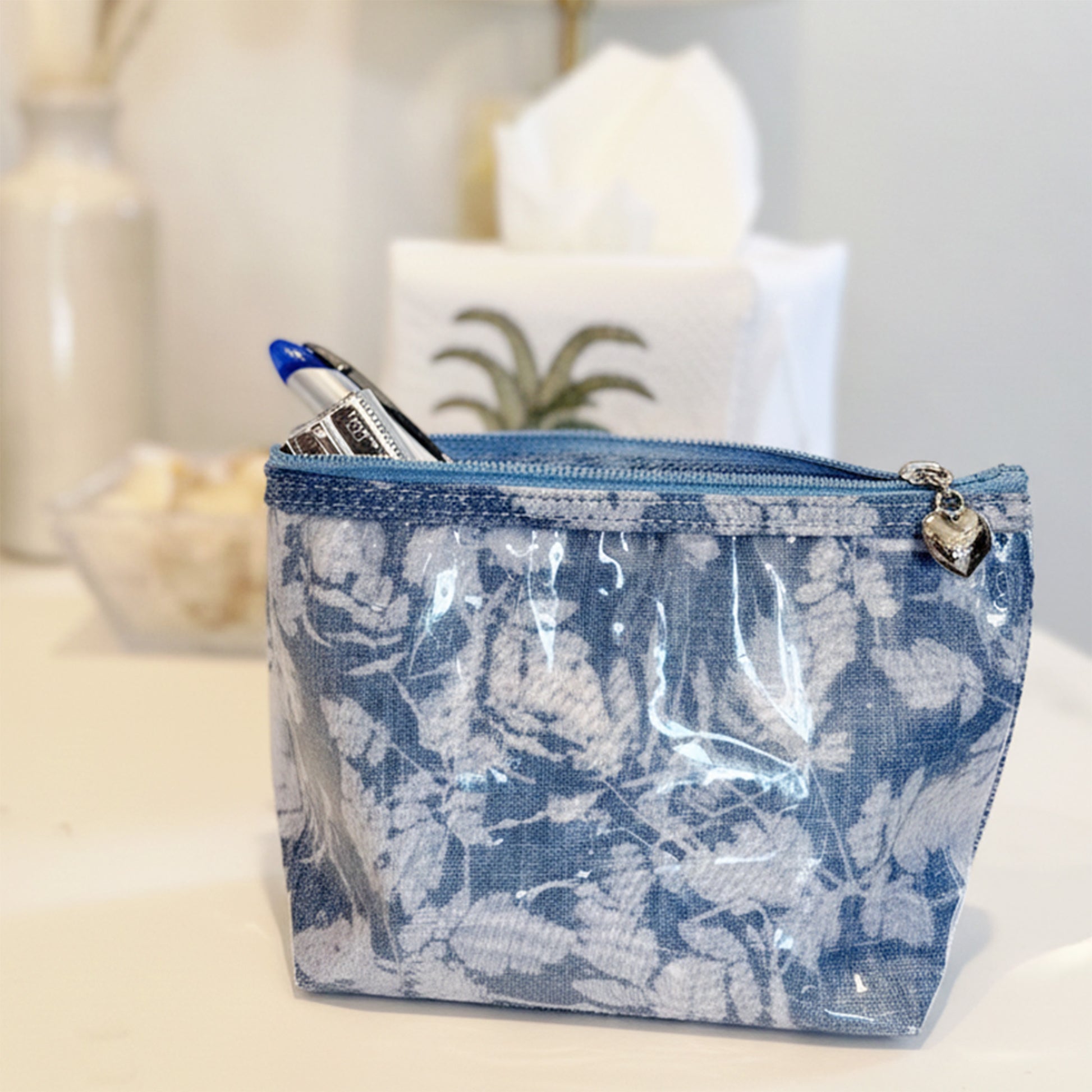 Blue floral-patterned pouch with a clear front on a white surface