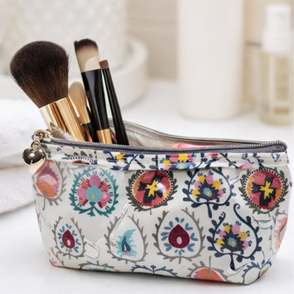 Makeup bag with floral pattern containing makeup brushes on a light background