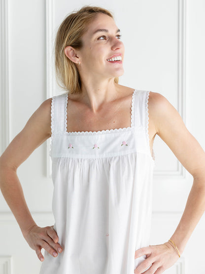 Woman wearing a white nightgown with lace details against a white background