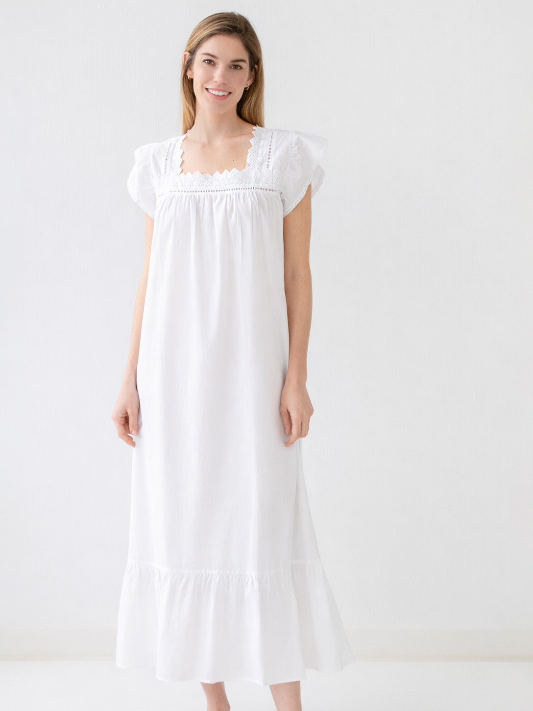 Woman wearing a white nightgown against a plain background