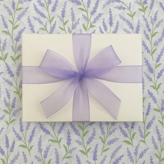 Gift box with a purple ribbon on a lavender patterned background