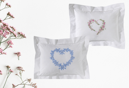 Two embroidered pillows with heart designs on a white background with pink flowers.