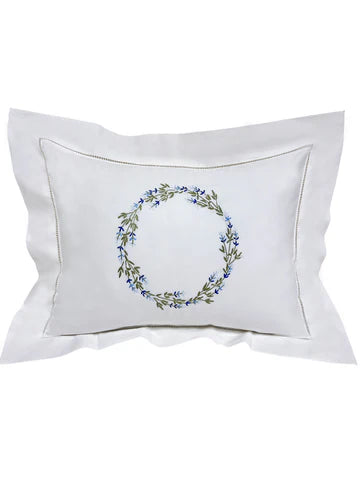 White pillow with floral wreath design on a white background